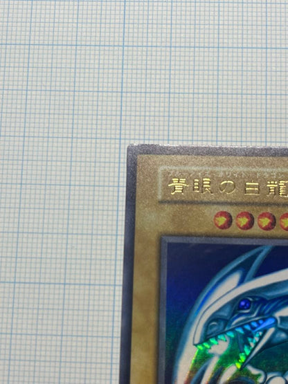 Yugioh Blue-Eyes White Dragon Ultra Rare trading card with light surface scratches and a small dent in the center