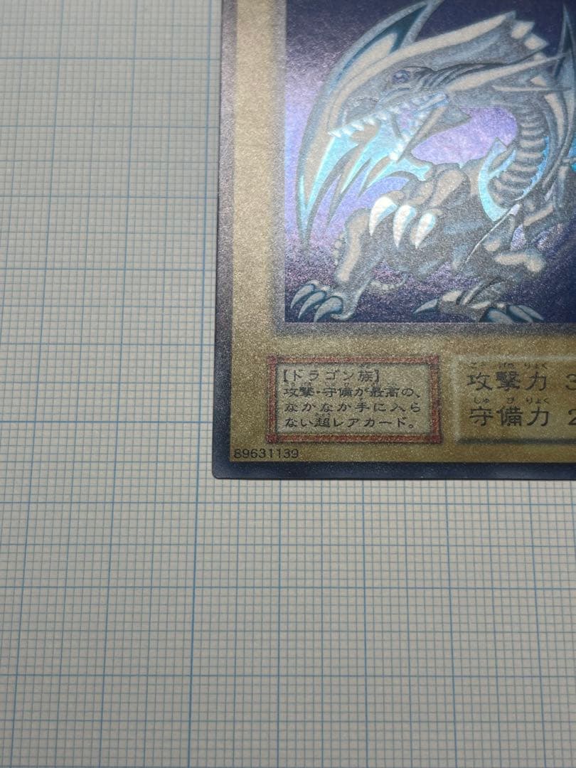 Yugioh Blue-Eyes White Dragon Ultra Rare trading card with light surface scratches and a small dent in the center