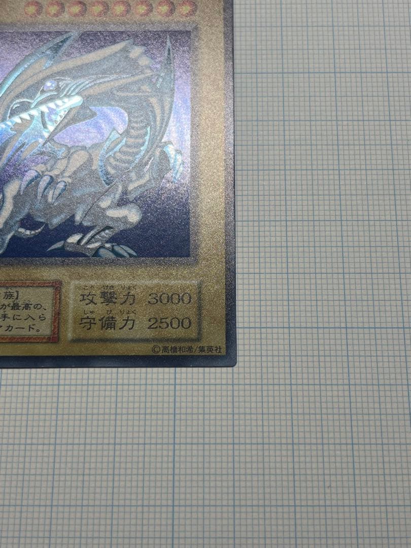 Yugioh Blue-Eyes White Dragon Ultra Rare trading card with light surface scratches and a small dent in the center