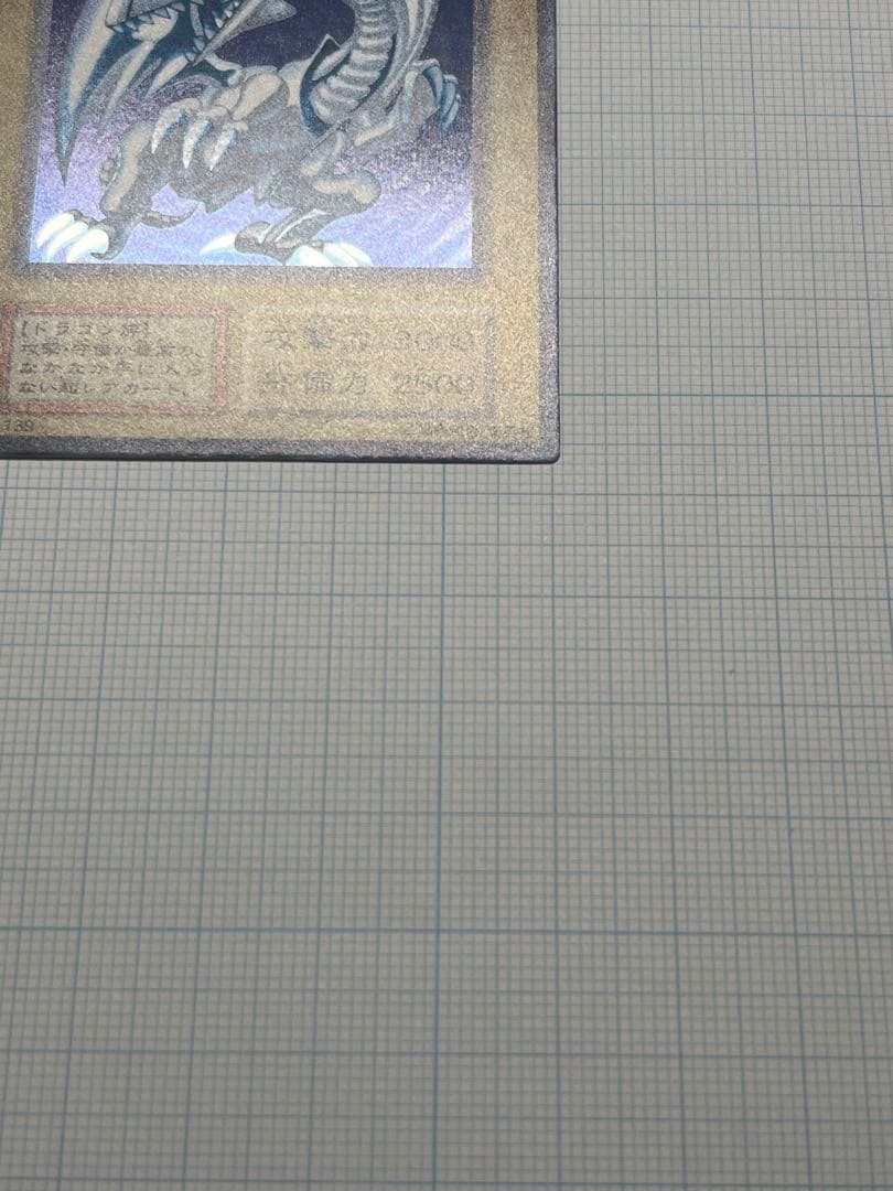 Yugioh Blue-Eyes White Dragon Ultra Rare trading card with light surface scratches and a small dent in the center