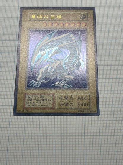 Yugioh Blue-Eyes White Dragon Ultra Rare trading card with light surface scratches and a small dent in the center