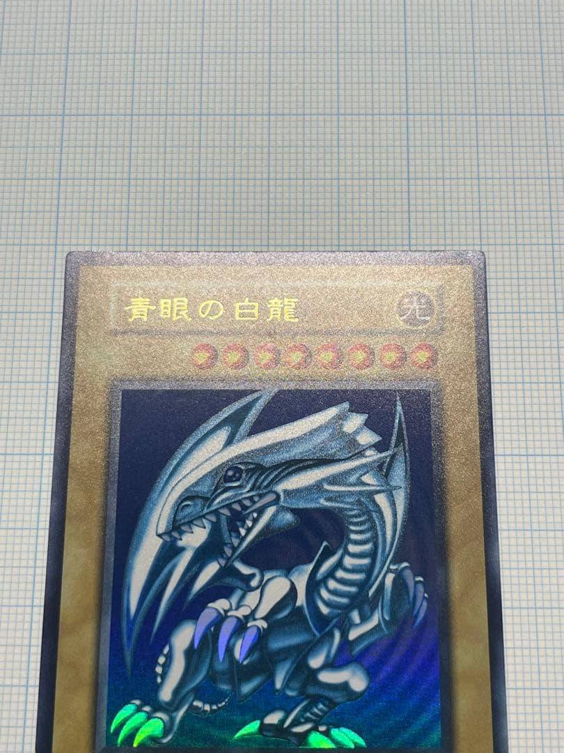 Yugioh Blue-Eyes White Dragon Ultra Rare trading card with light surface scratches and a small dent in the center