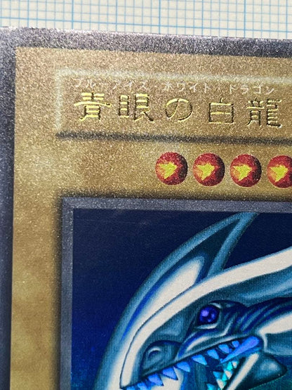 Yugioh Blue-Eyes White Dragon Ultra Rare trading card with light surface scratches and a small dent in the center