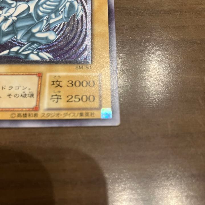 Blue-Eyes White Dragon Relief Card SM-51 with visible wear and a small white chip, Japanese Yu-Gi-Oh collectible