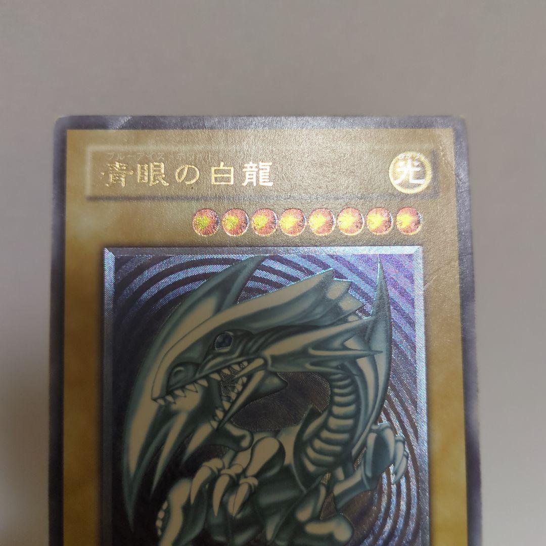 Blue-Eyes White Dragon Ultra Rare card collectible with 3000 attack, 2500 defense, chipped top and back, clean blue body