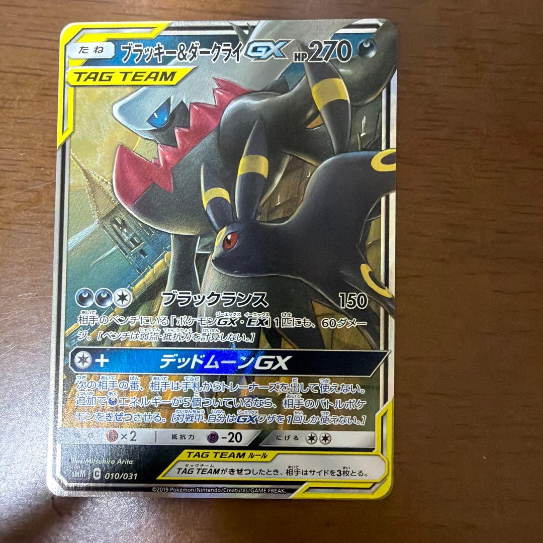 Bastus Black & Darkrai GX trading card with minor wear, displayed on a shelf
