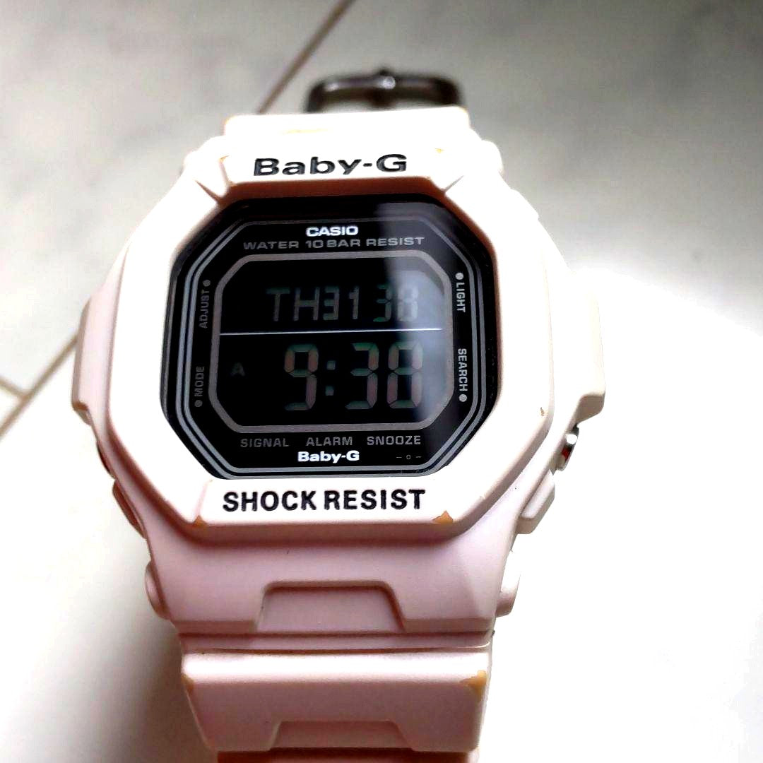 Casio Baby-G BG-5600 white digital watch showing signs of heavy use, scratches, and discoloration