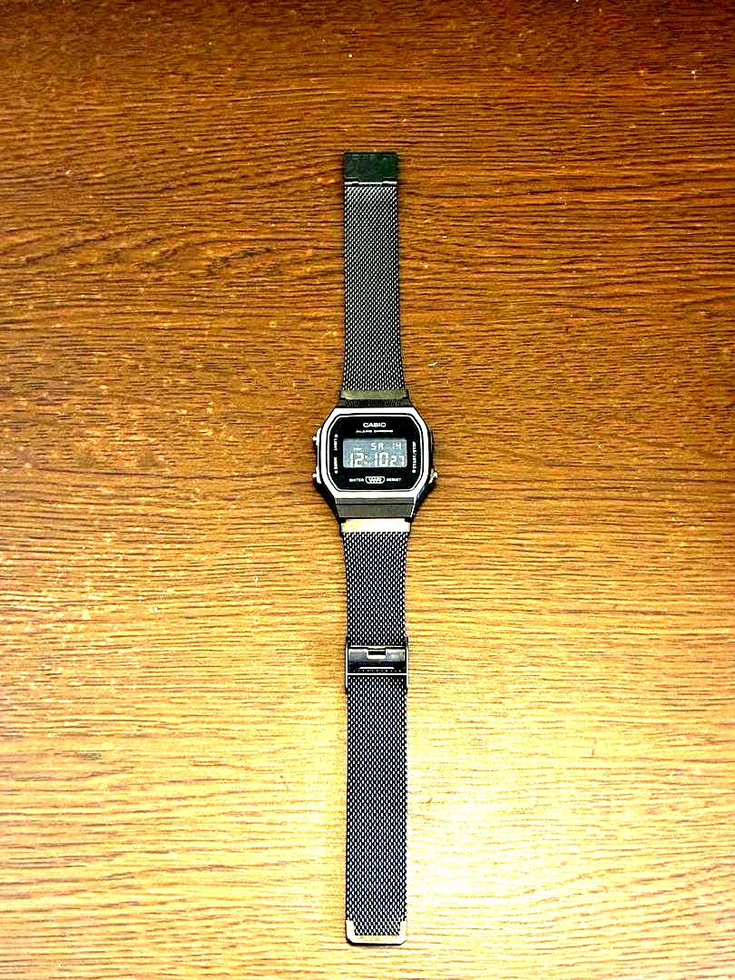 Casio digital watch with black mesh band showing classic digital display