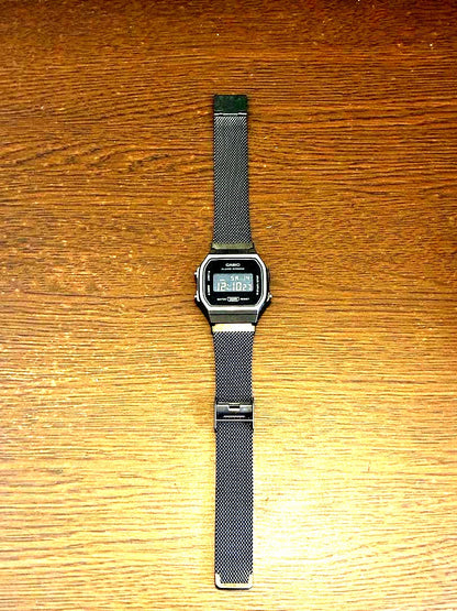 Casio digital watch with black mesh band showing classic digital display
