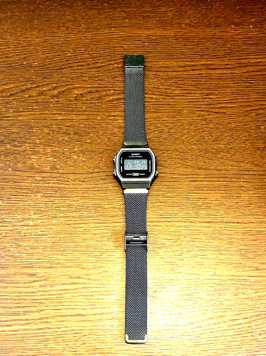Casio digital watch with black mesh band showing classic digital display