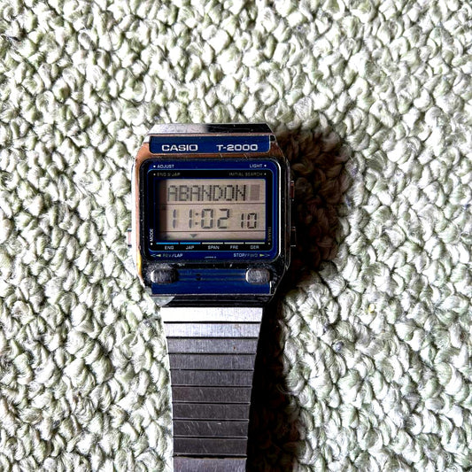 Casio T-2000 digital watch with stainless steel band showing time display and buttons