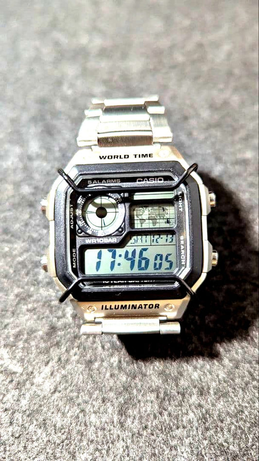Casio AE-1200WH watch showing digital display and black glass surface protector attached