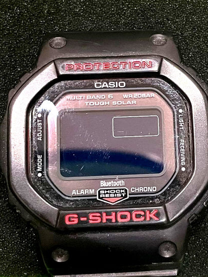 Casio G-Shock DW-5600 digital watch with black and red resin band showing dark screen and resin strap
