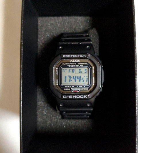 Casio G-Shock GW-5000-1JF digital watch showing EL backlight, used band and bezel with scratches