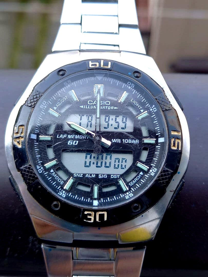 Casio AQ-164W dual time watch with black dial and silver bracelet showing 10 bar water resistance