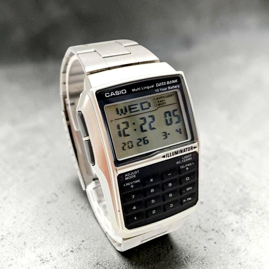 Casio Data Bank DBC-32 digital watch with silver and black retro face, calculator, and world time features