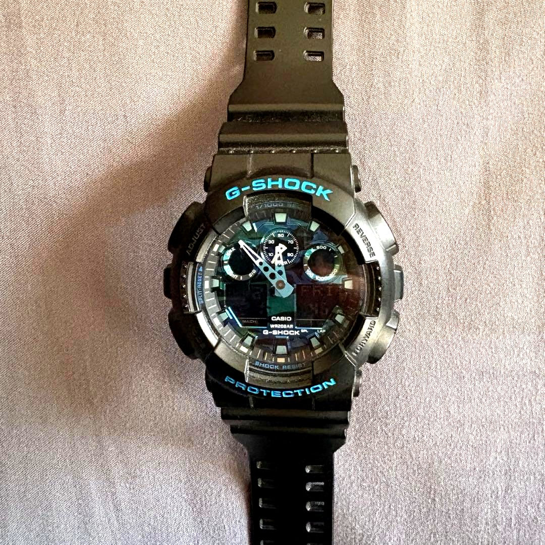 Casio G-Shock GA-100CB watch with digital and analog display in black and blue camouflage pattern