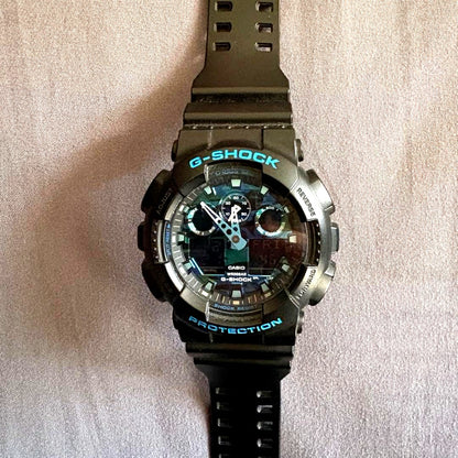 Casio G-Shock GA-100CB watch with digital and analog display in black and blue camouflage pattern