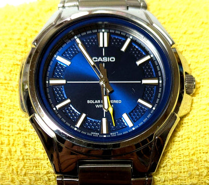 Casio RS100 solar watch featuring navy dial and yellow arrow hands with metal links