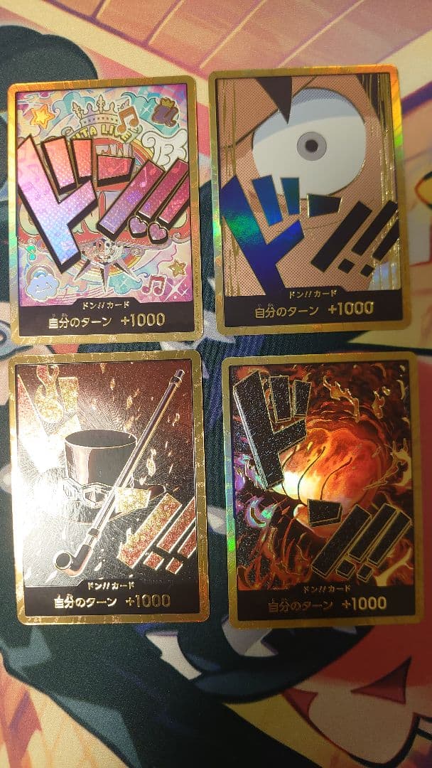 One Piece Card Game cards featuring Sabo, Luffy, Uta, and Akainu with gold borders in protective sleeve