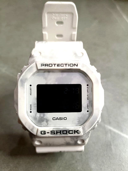 Casio G-Shock DW-5600GC-7JF watch with white digital display and grunge snow camouflage pattern