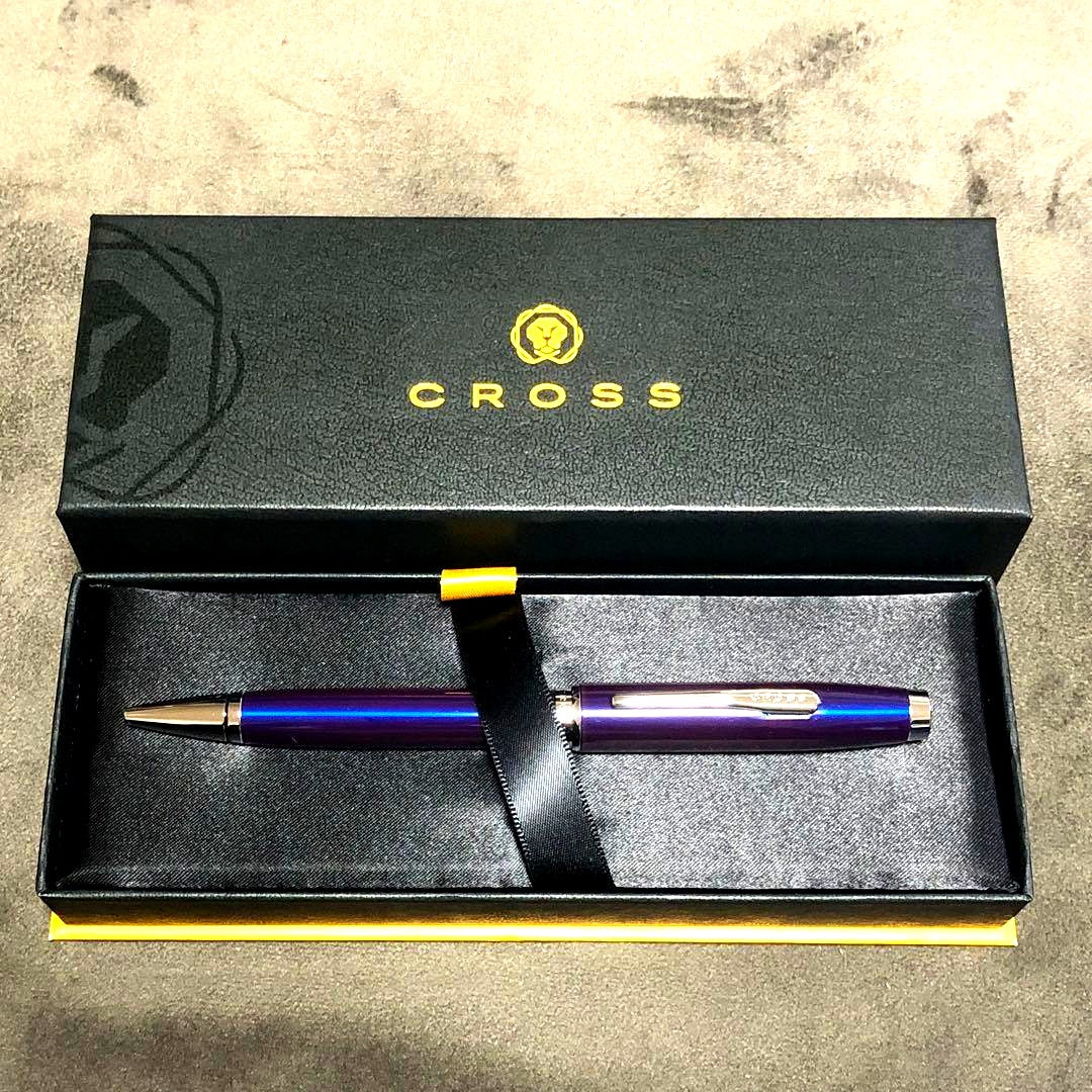 Blue metal-bodied Brand Crossball ballpoint pen with silver tip and visible scratch on glossy surface