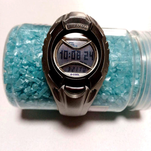 Casio G-Cool wristwatch with clear glass, metal band, and user manual included