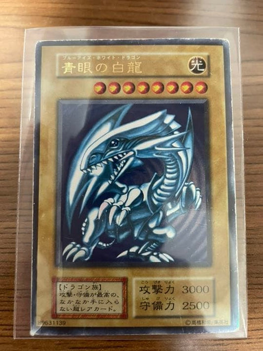Yu-Gi-Oh Blue-Eyes White Dragon early edition trading card with visible wear and protective sleeve