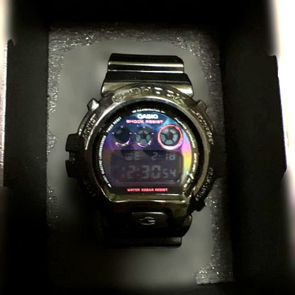 Casio G-SHOCK DW-6900RGB-1JF digital watch with rainbow detailing, black strap, displayed with box and manual
