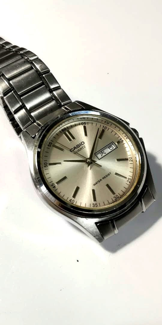 Casio silver analog wristwatch with date display showing stopped time