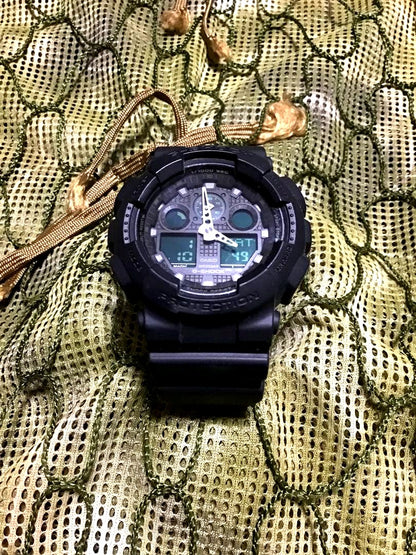 Casio G-Shock GA-100MB black watch with rubber band showing front dial and display