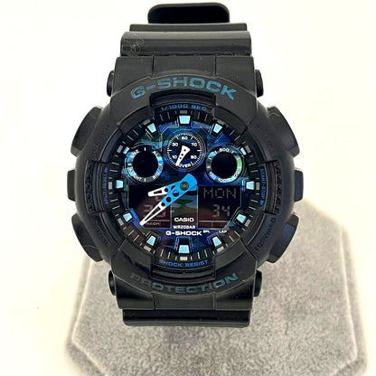 Used Casio G-Shock GA-100CB watch with camouflage pattern showing scratches on glass and band