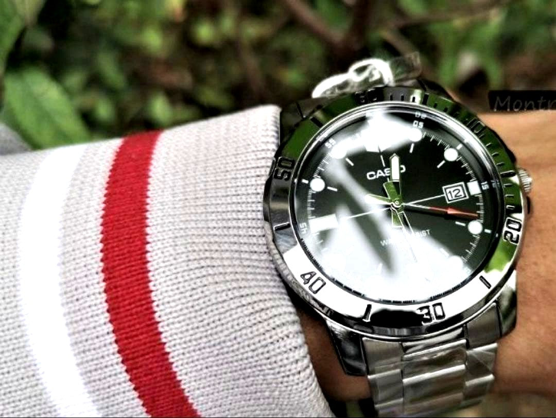 Casio analog wristwatch with large black dial, silver stainless steel band, and mineral glass face