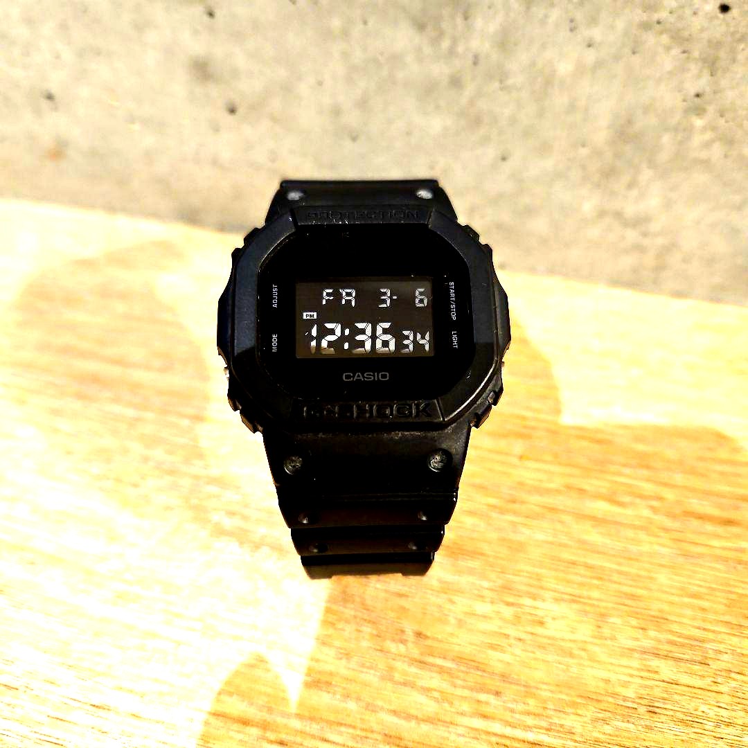 Casio Digital Watch DW5600 all black with rubber band showing front display and strap