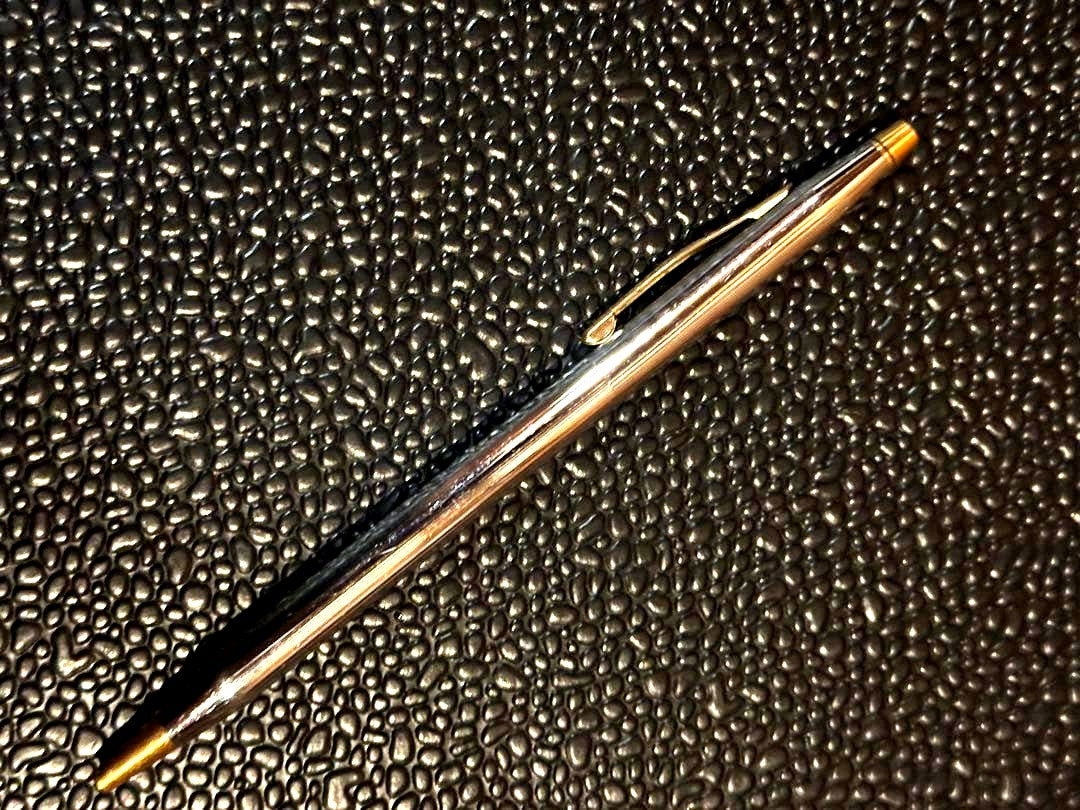 Cross ballpoint pen with silver and gold body, dark blue ink, made in USA, showing signs of use