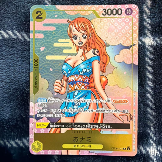 Used One Piece Card Game Nami R OP06-101 promotional card showing minor scratches and stored in protective sleeve