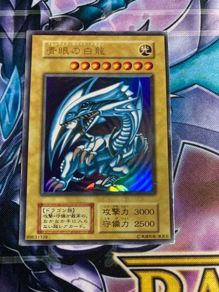 Sony Ultra Rare Blue-Eyes White Dragon Yu-Gi-Oh card showing light edge wear and scratch damage