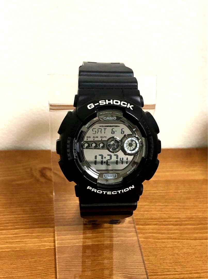 Casio G-Shock GD-100BW black digital watch showing front view with band and illuminated light