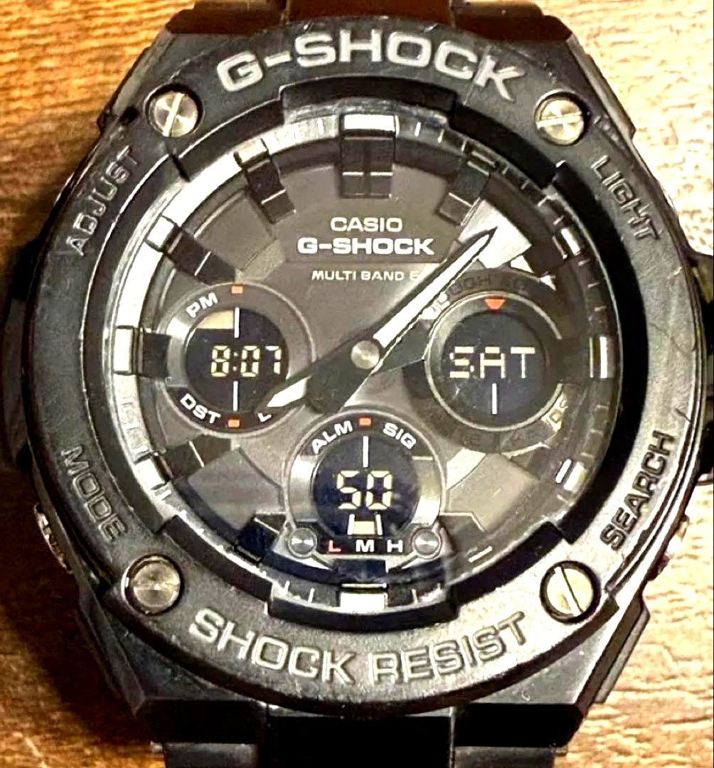 Casio G-Shock GST-W100G black solar watch showing radio wave feature with minor wear