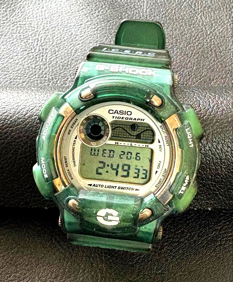 Casio G-Shock DW-8600KJ-7T digital watch with titanium back and green resin band displaying tidegraph