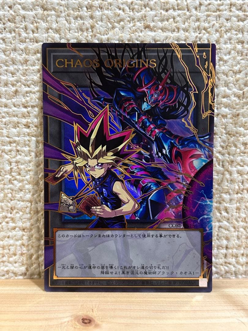 Chaos Origins Token displayed in protective sleeve on a plain surface
