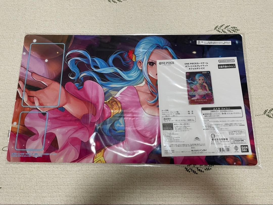 One Piece Badge Neferutari Vivi character playmat with promo card made of polyester and rubber folded in packaging