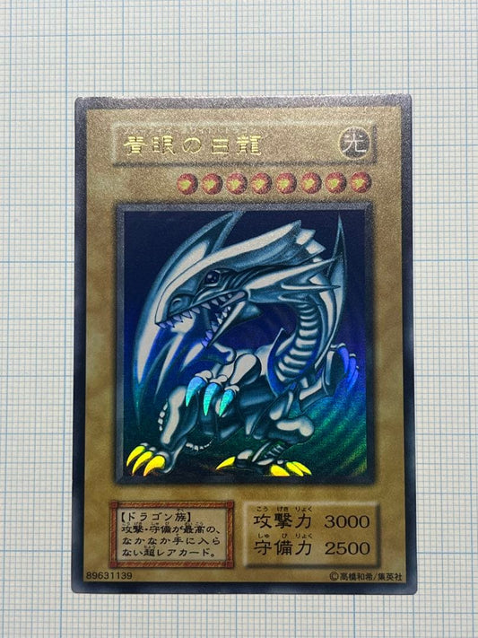 Yugioh Blue-Eyes White Dragon Ultra Rare trading card with light surface scratches and a small dent in the center