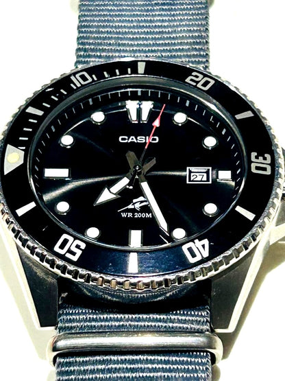 Casio WR 200M analog watch with black dial, nylon band, and date display
