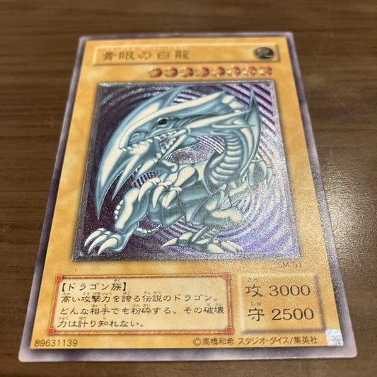 Blue-Eyes White Dragon Relief Card SM-51 with visible wear and a small white chip, Japanese Yu-Gi-Oh collectible